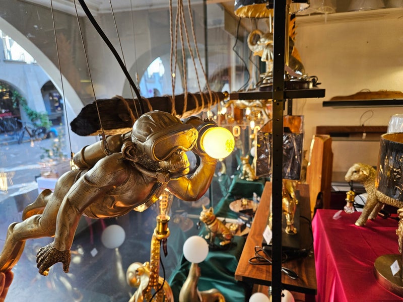 Schaufenster von Gassenlicht mit goldener Taucheraffen-Leuchte an der Münstergasse in Bern